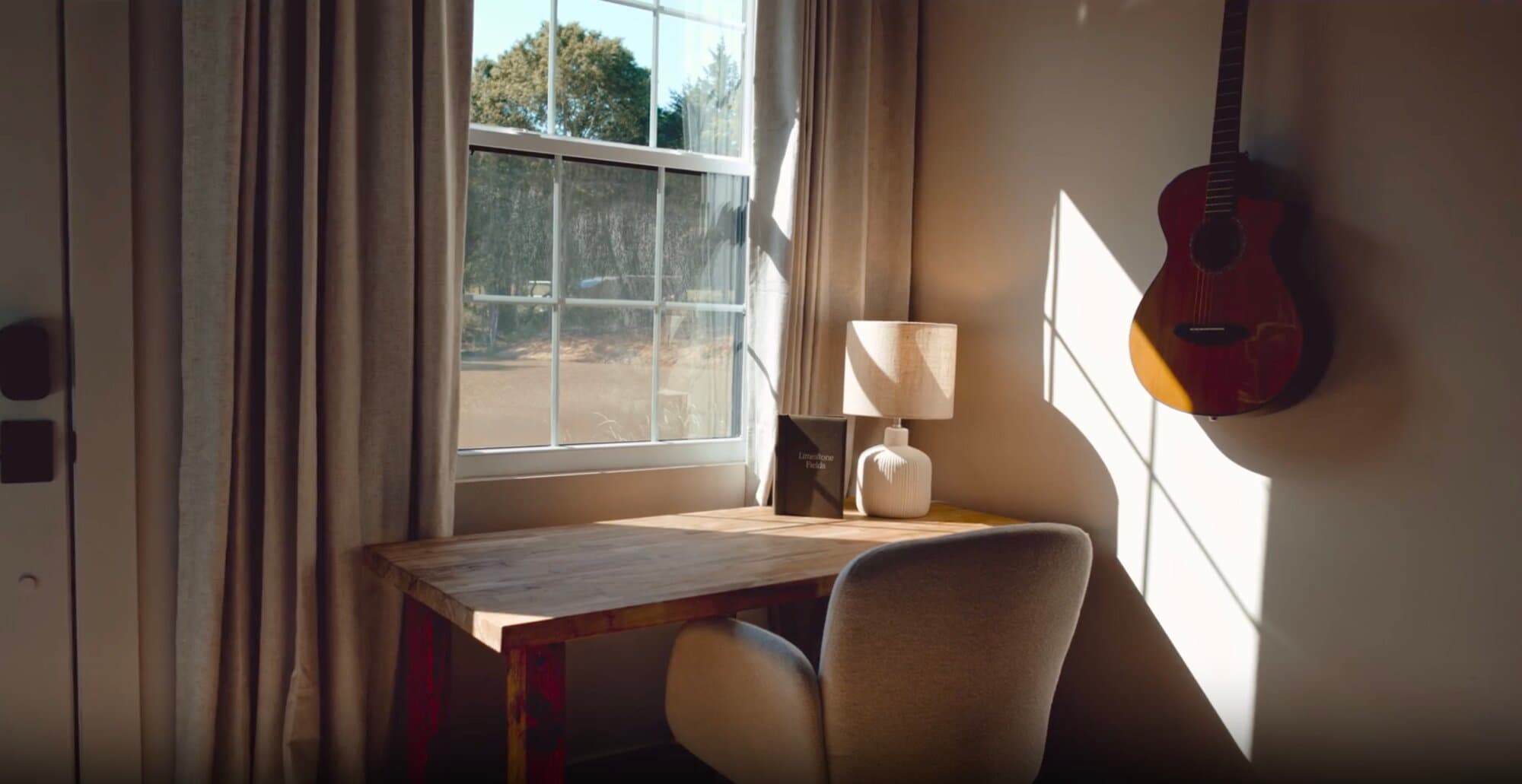 Deep work retreat in Texas — a desk by the window with a guitar on the wall, set up for quiet focus