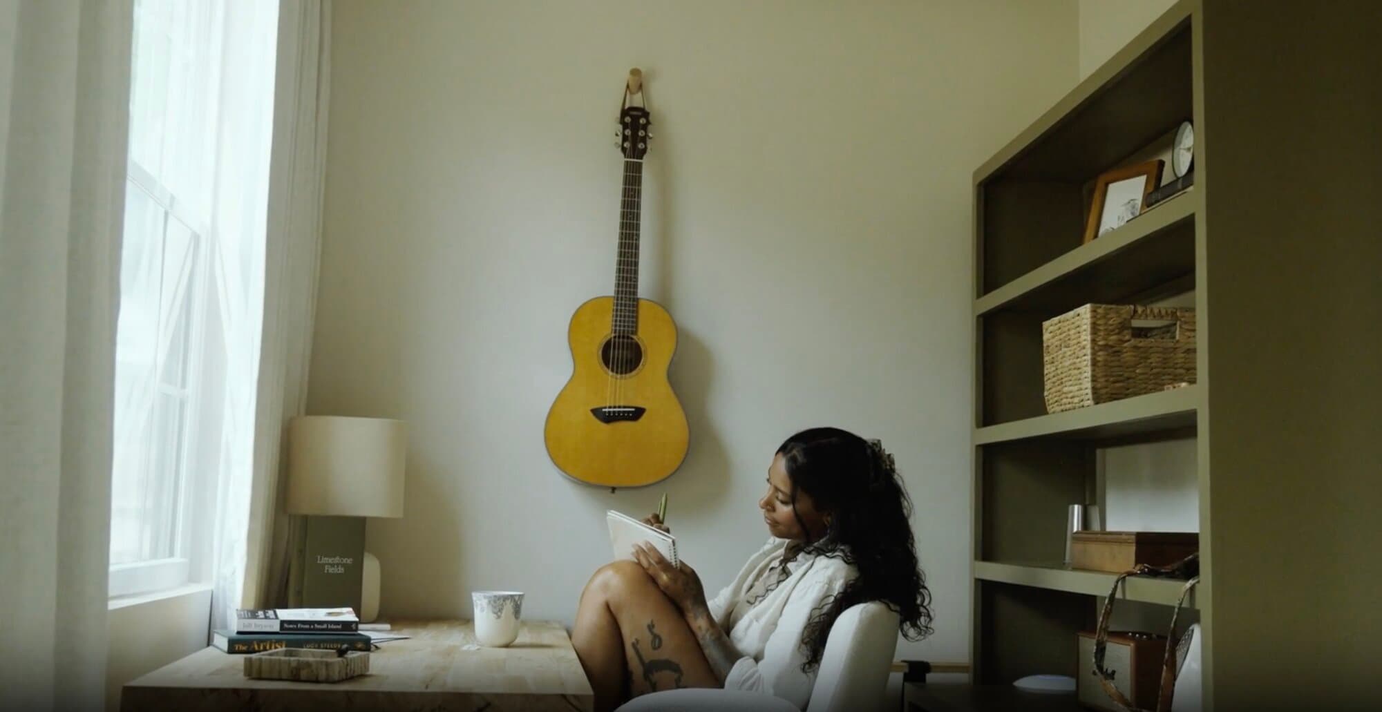 A guest writing in a journal beneath a hanging guitar, deep work retreat in Texas