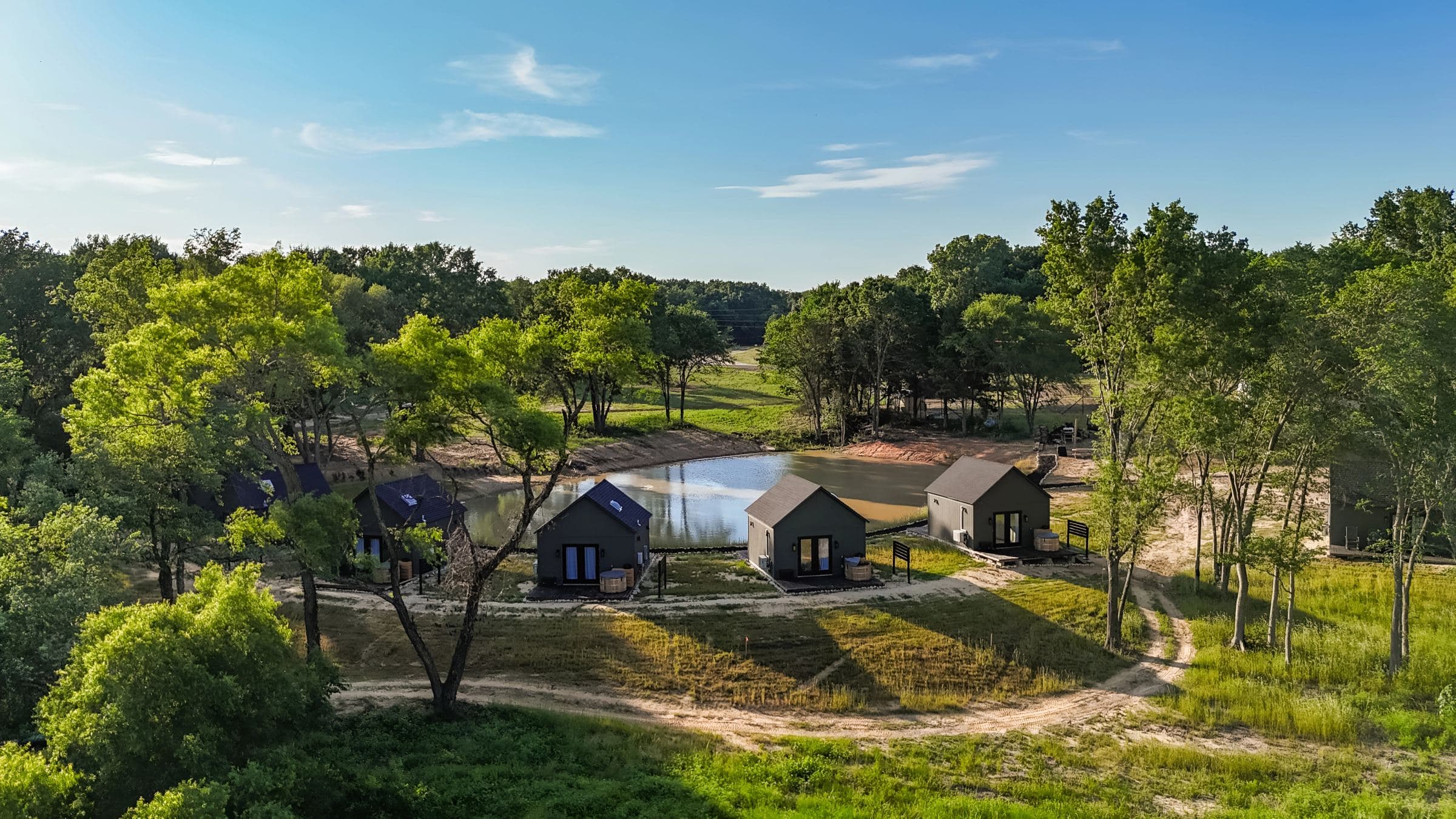 Aerial view of the cabins around the pond at Limestone Fields, with Lake Limestone beyond