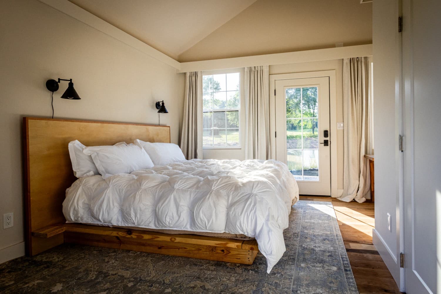 Inside a cabin: king bed, wood headboard, and a glass door onto the deck