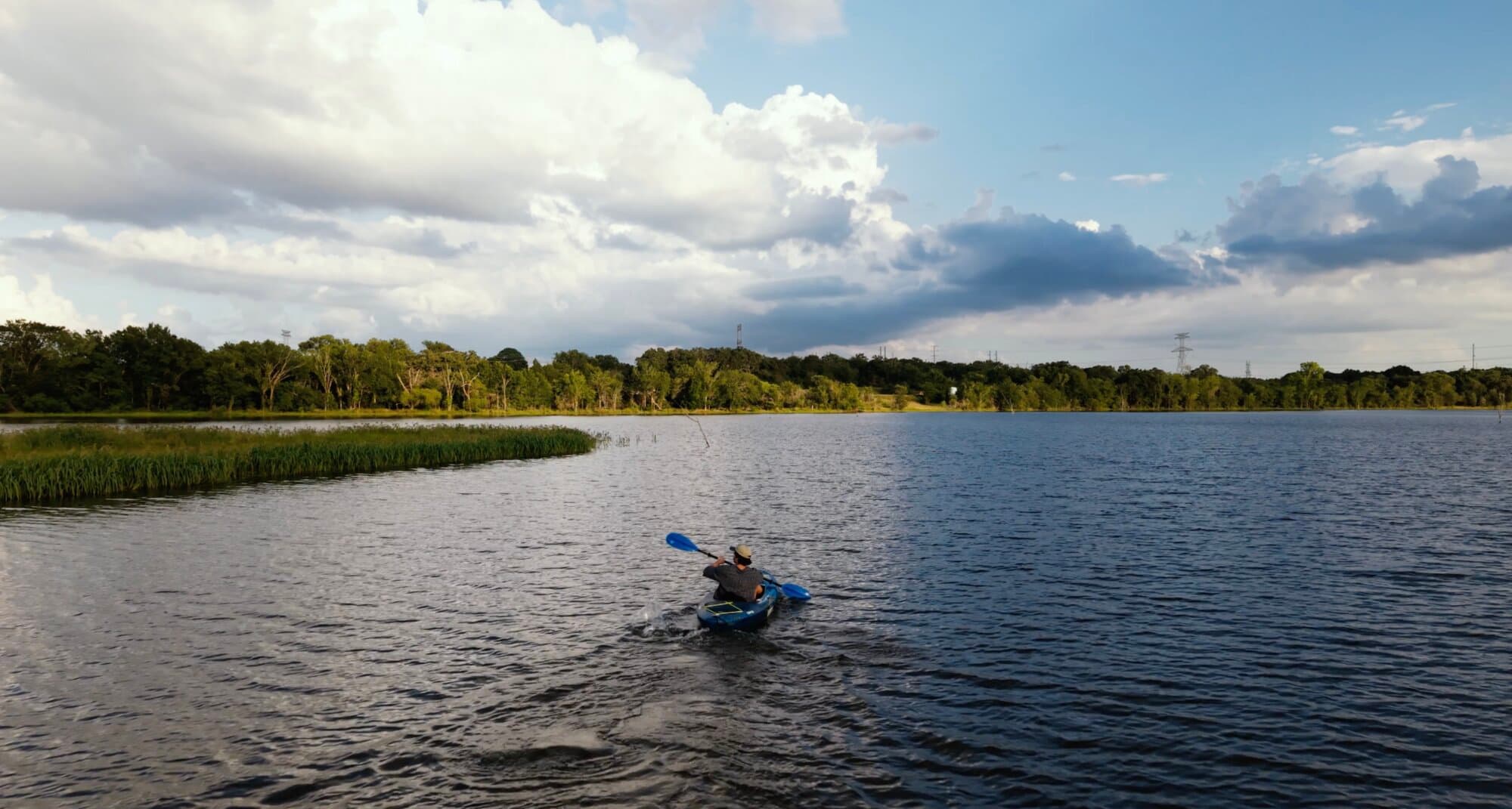 A guest kayaking across Lake Limestone under a big sky