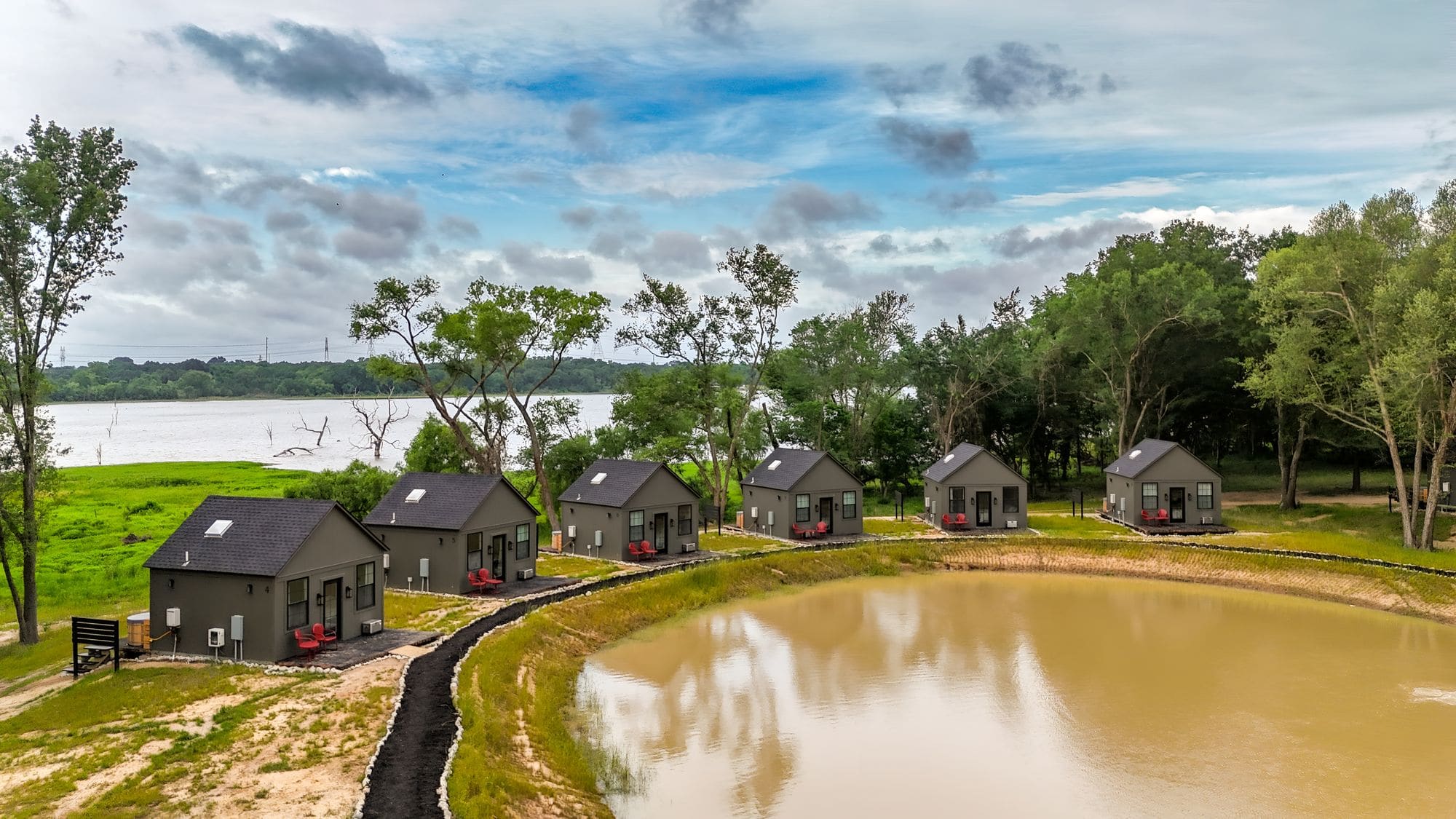 Aerial view of cabins curving around the pond with the lake behind