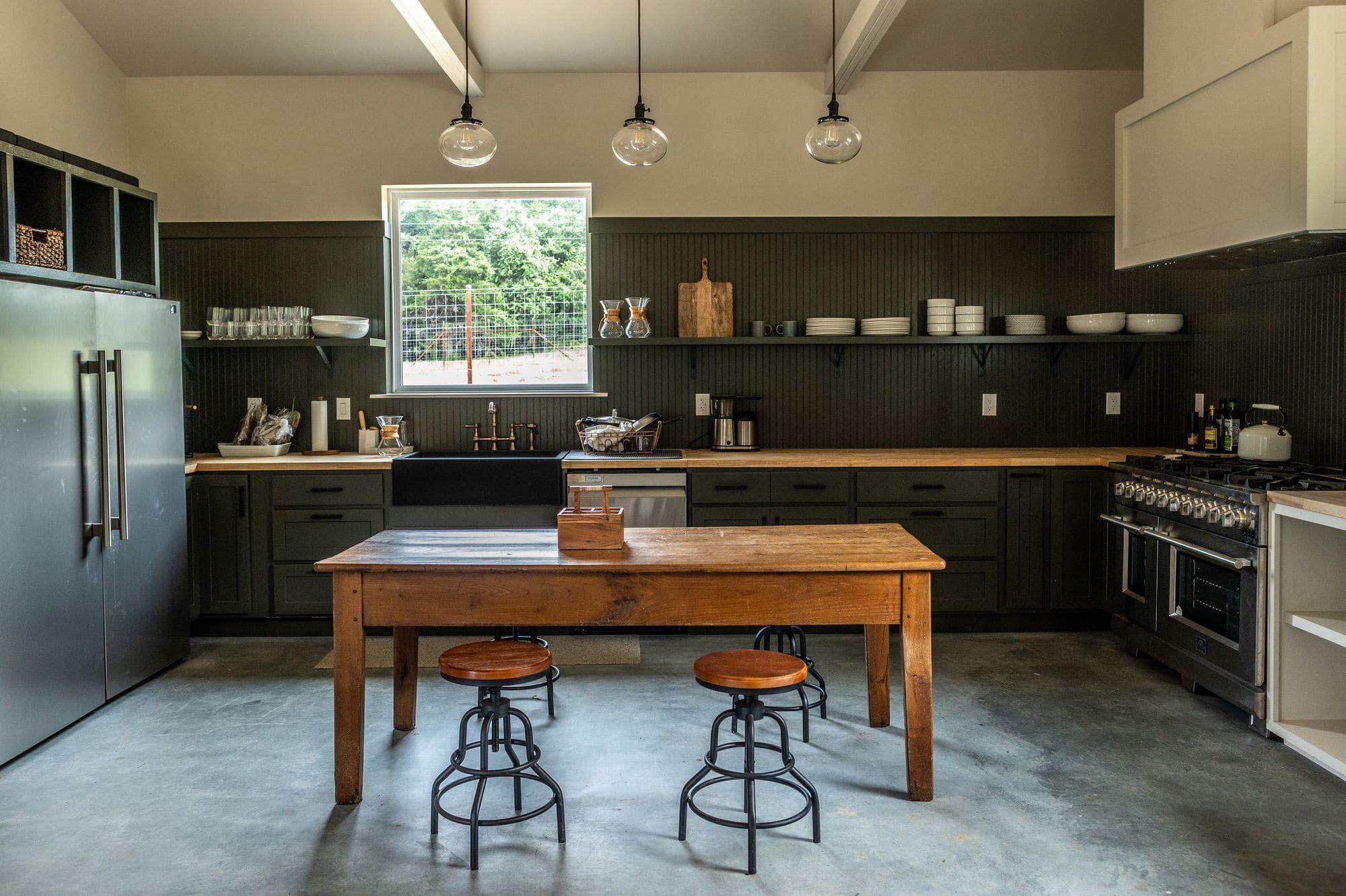 Commons barn kitchen with a long farm table, steel fridge and pendant lights