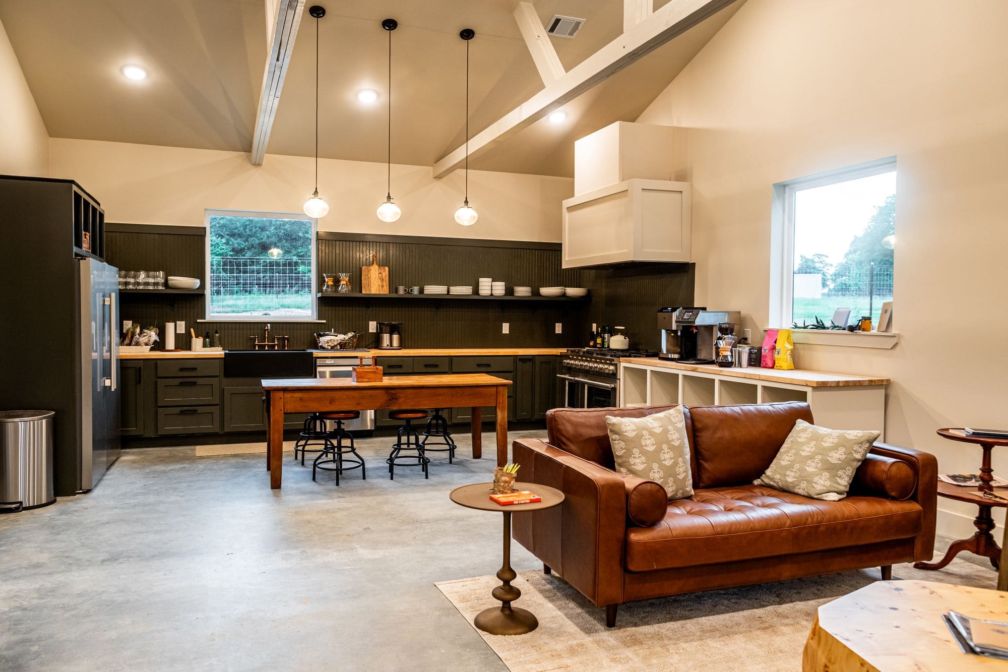 Commons barn open kitchen with a farm table, pendant lights and a leather sofa