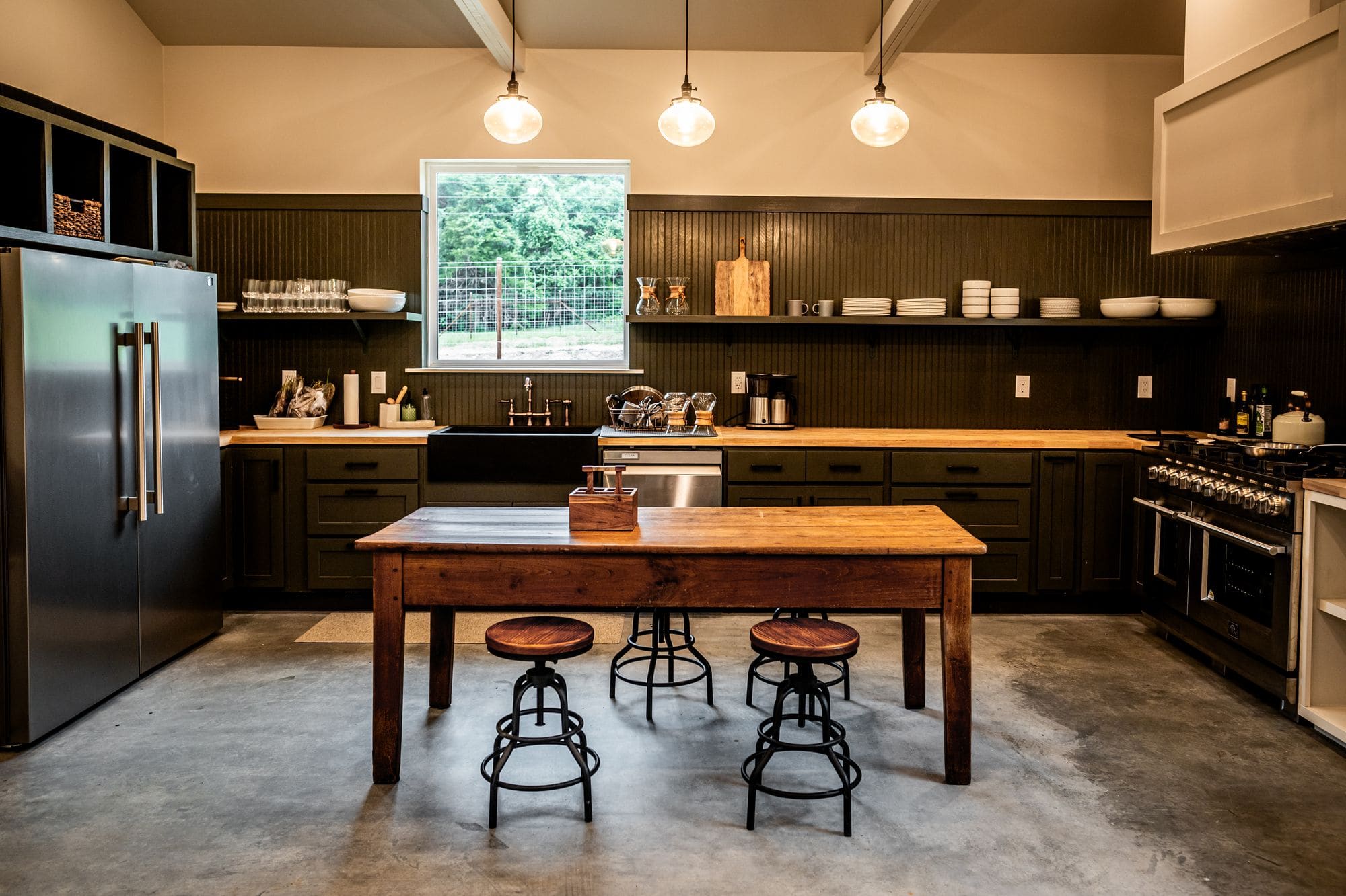Commons barn kitchen with a wooden farm table and metal stools