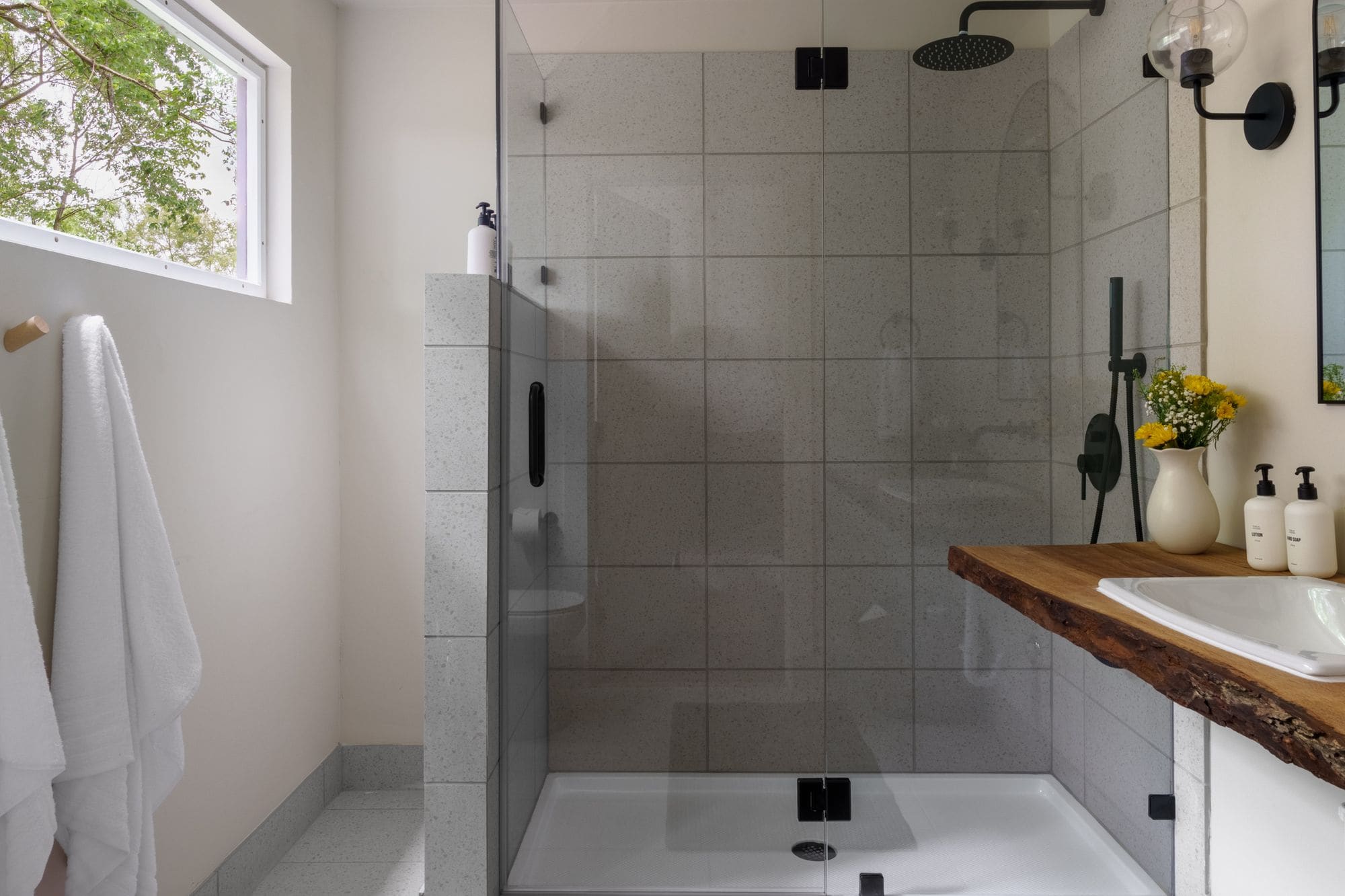 Cabin bathroom with a glass walk-in shower, tile walls and a window