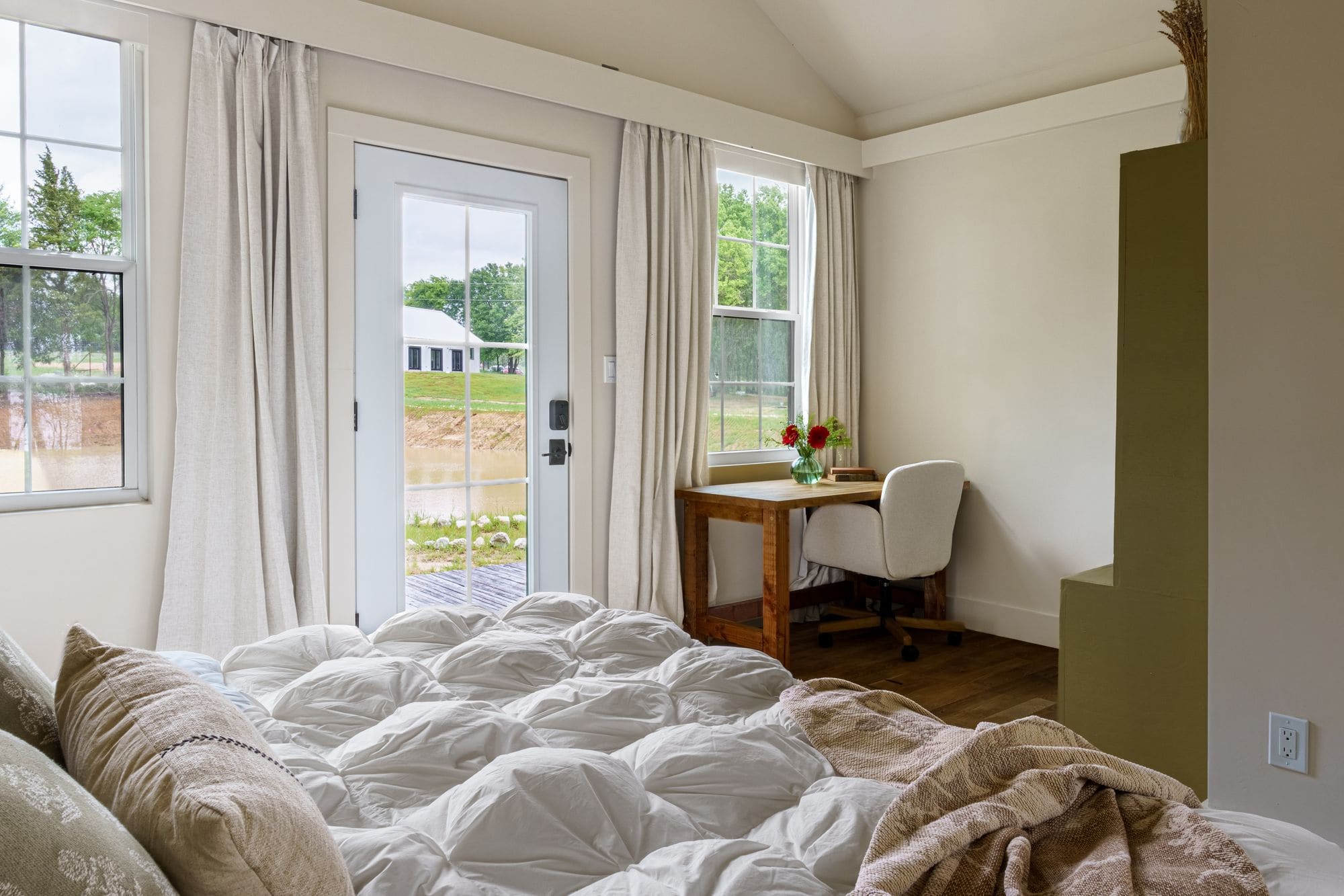 Cabin bed in the foreground with French doors to the porch and a writing desk by the window