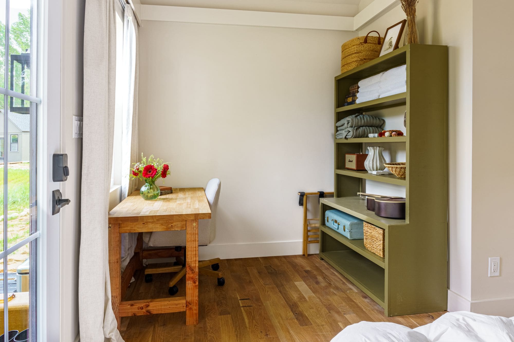 Cabin writing desk, bookshelf and an open door to the porch in soft daylight