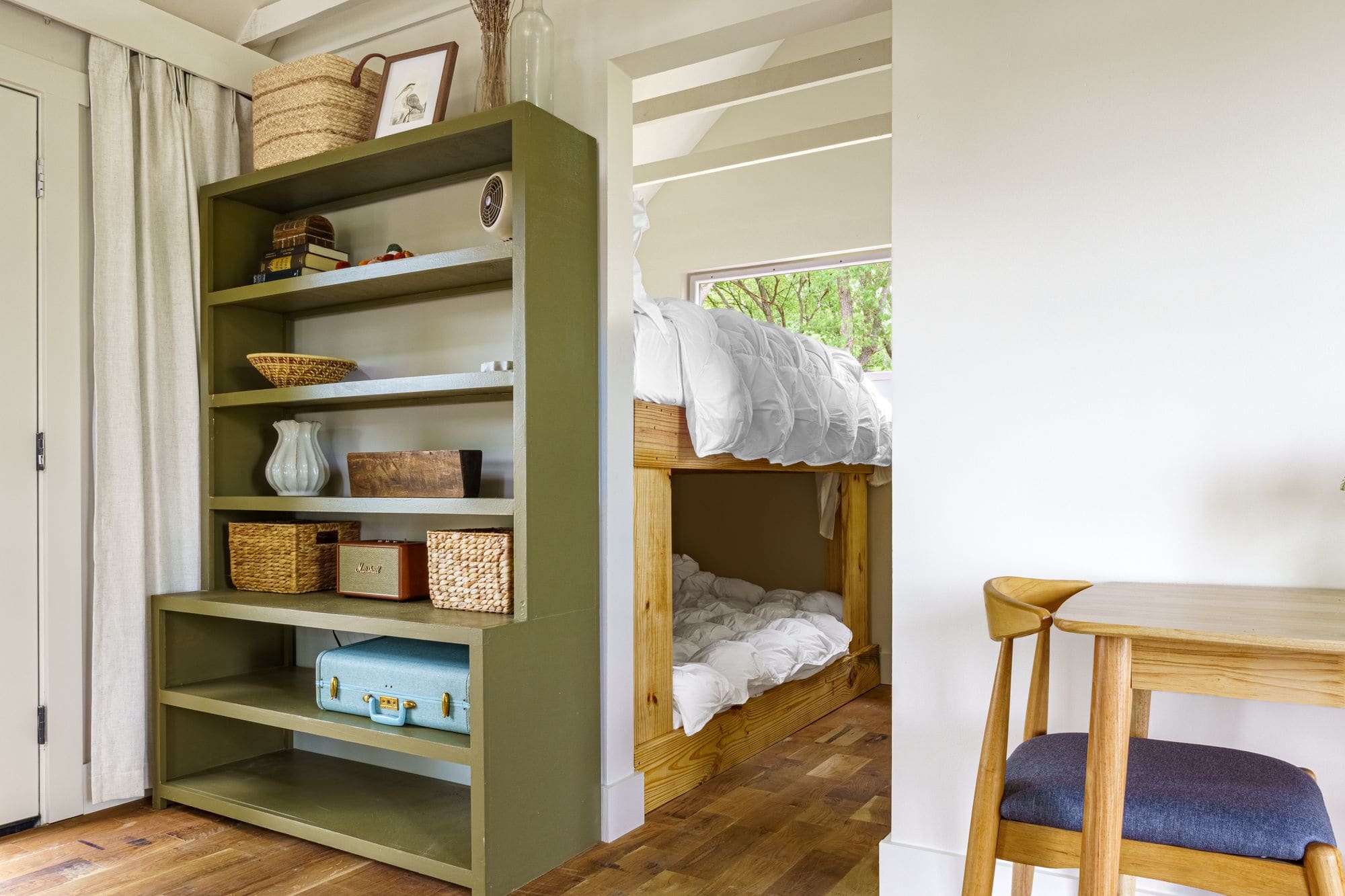 Bunk beds tucked behind the olive-green bookshelf in a cabin
