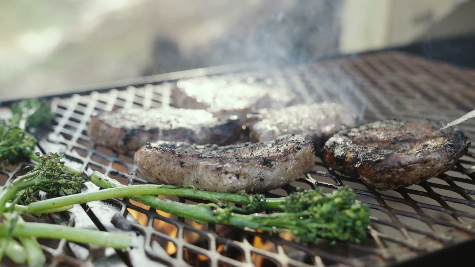 Steaks sizzling over the flames on the outdoor grill