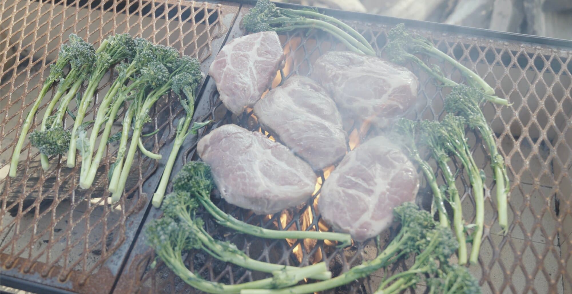 Steaks and broccolini cooking on the Santa Maria grill at a Texas corporate retreat venue